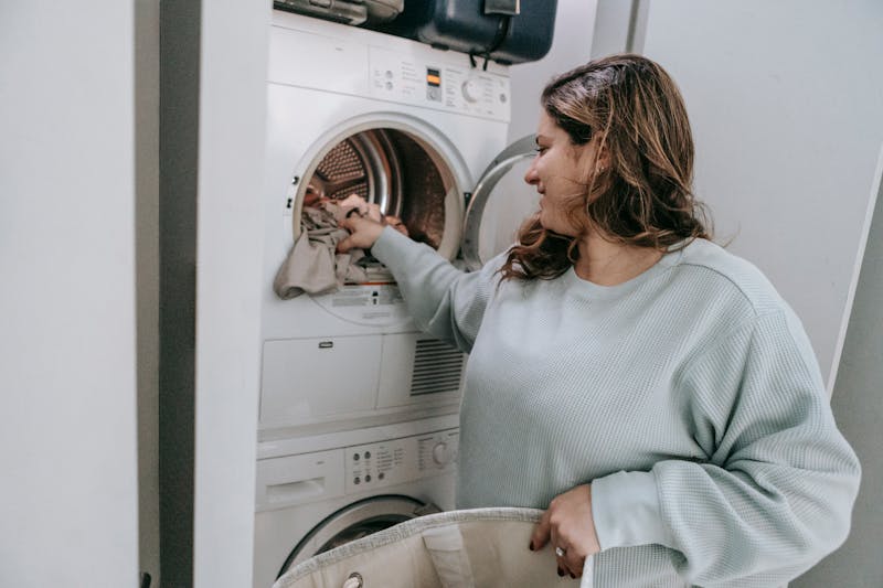 Woman loading Samsung dryer in home laundry room